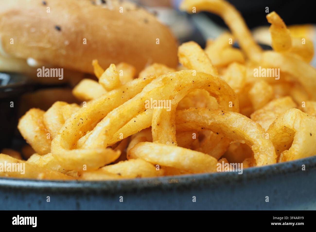 Geschwungene Pommes und Burger serviert auf einem Teller in einem Restaurant Stockfoto