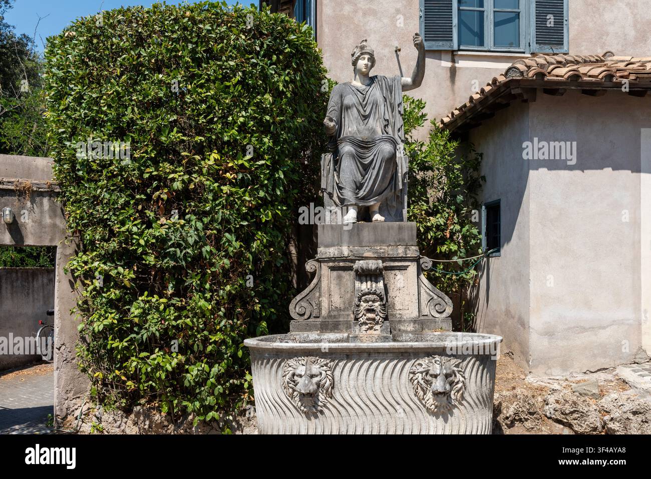 Monumentale sitzende Frauenfigur, die in einen ornamentalen Steinbrunnen mit Löwenmaske-Schnäbeln in der Villa Medici an der französischen Akademie in Rom integriert ist. Stockfoto