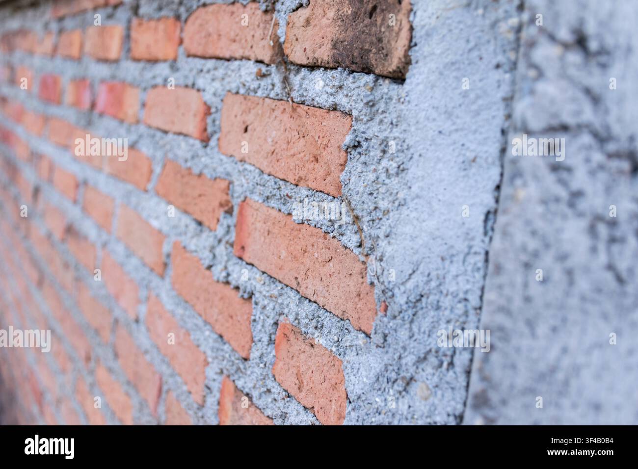 Nahaufnahme einer roten Ziegelwand mit Zementmörtel, die raue Mauertexturdetails und Handwerkskunst der Konstruktion zeigt, geeignet für Architektur und Bau Stockfoto