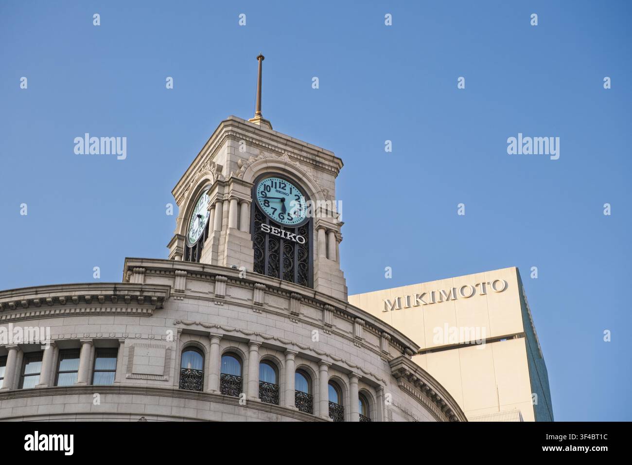 Tokio, Japan - 09. August 2025: Der markante SEIKO-Uhrenturm steht auf einem historischen Gebäude, während die Beschilderung VON MIKIMOTO auf einem modernen Gebäude in sichtbar ist Stockfoto