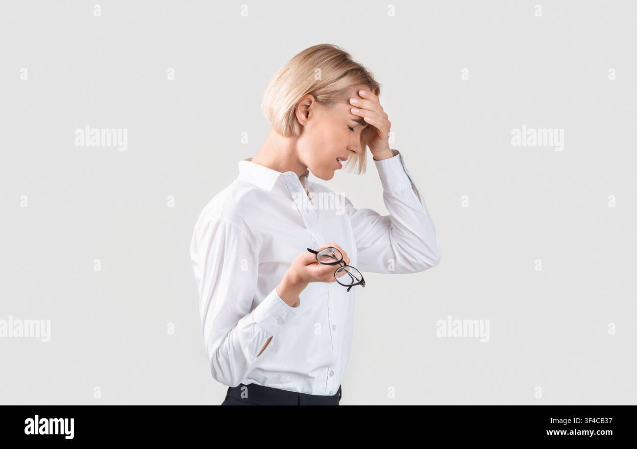 Überarbeiteter Unternehmer, der an Migräne, Müdigkeit oder Problemen auf hellem Hintergrund leidet Stockfoto