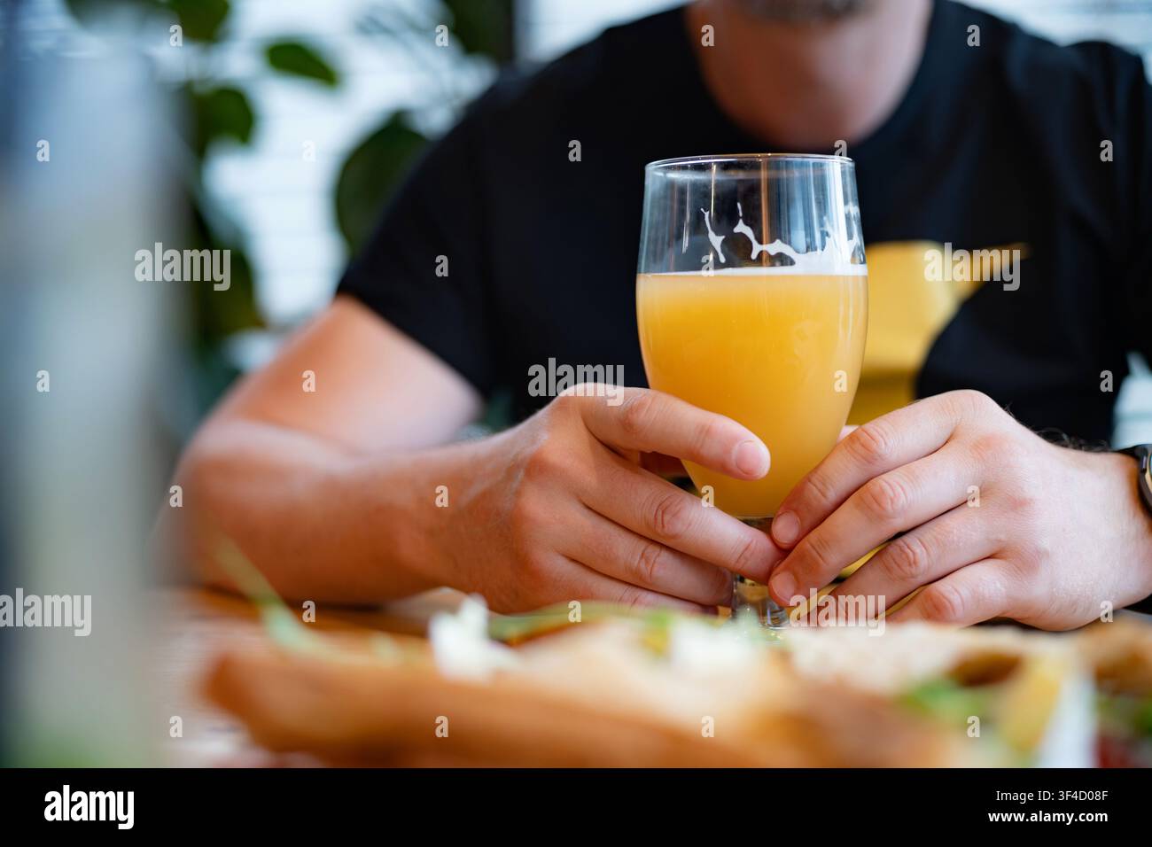 Mann trinkt weißes Weizenbier in einem gemütlichen Café Stockfoto