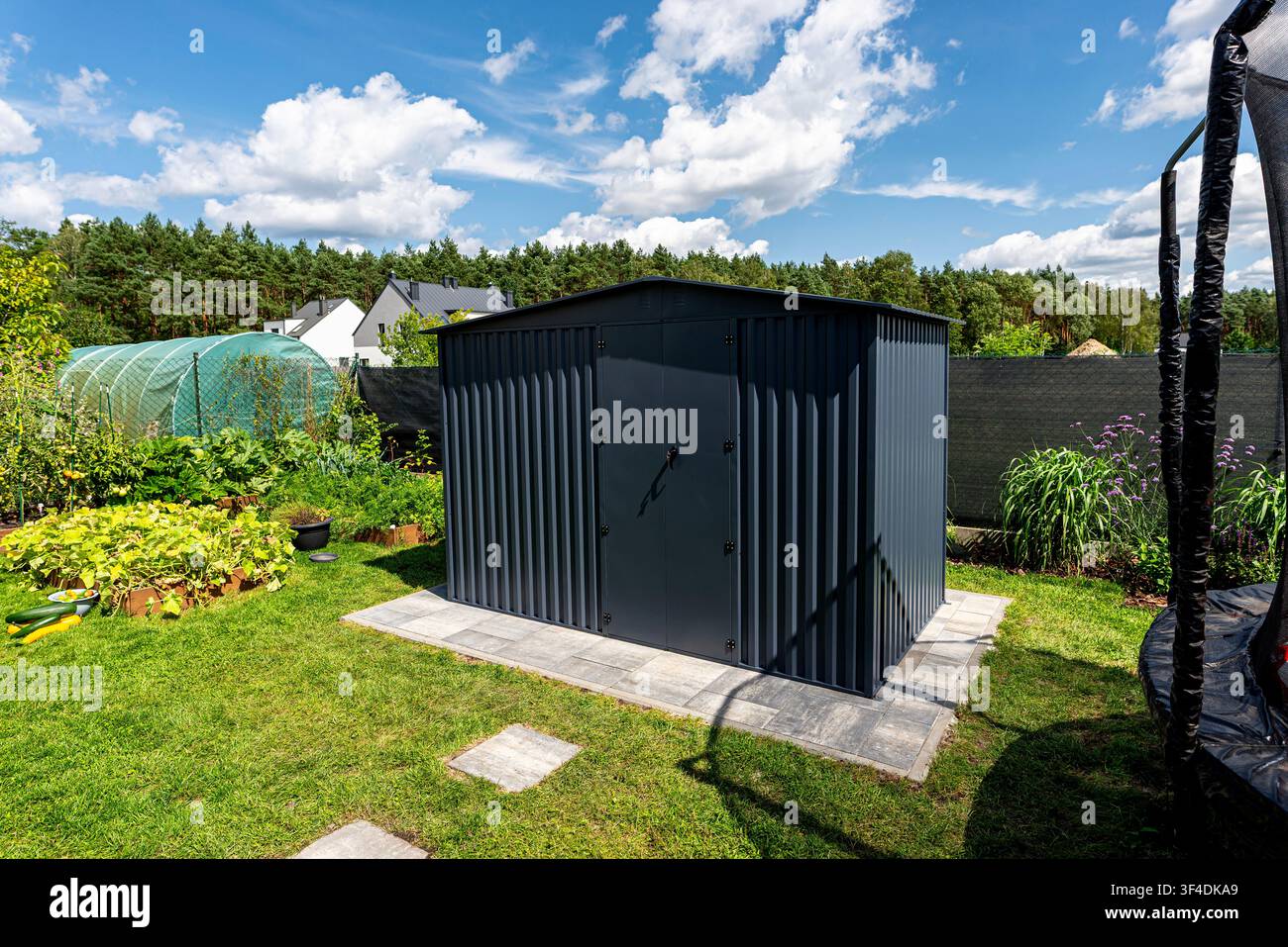 Gartenspeicher aus anthrazitfarbenem Wellblech auf einem Betonfundament Stockfoto