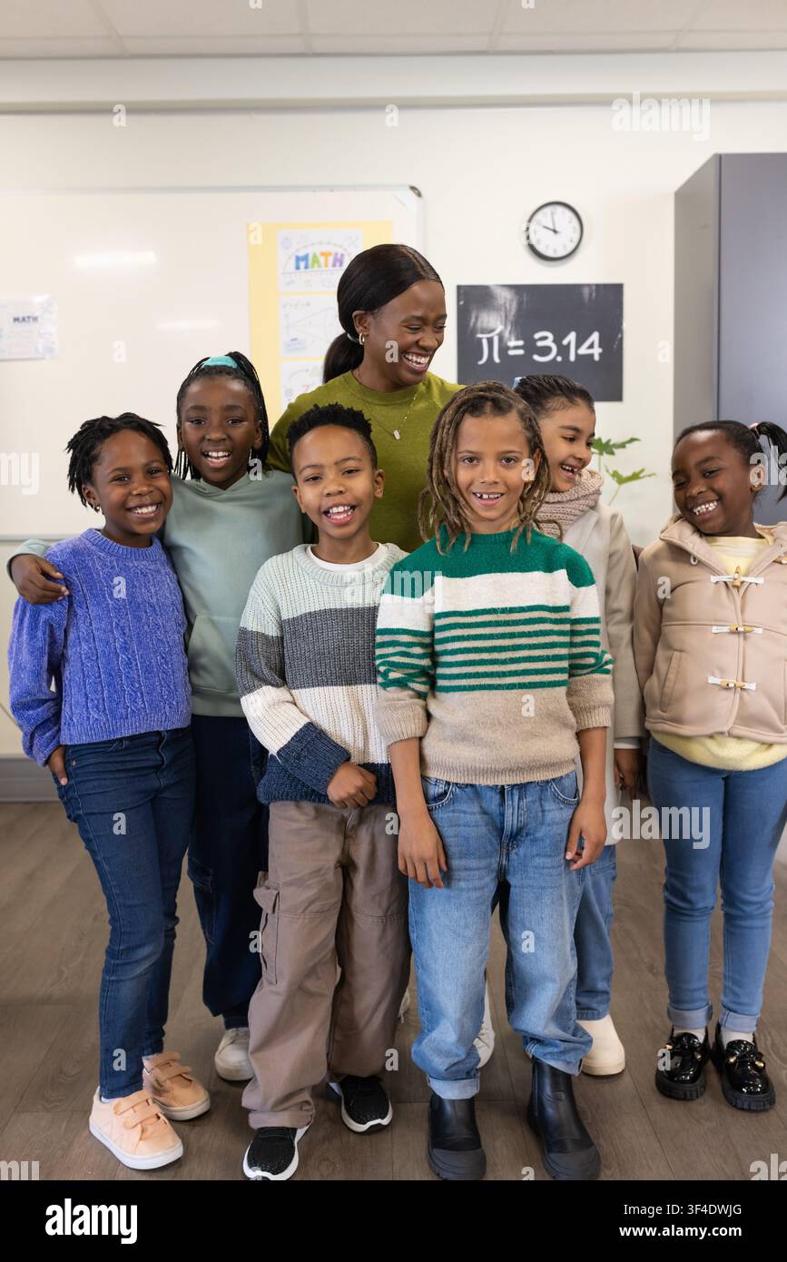 Afroamerikanische Lehrerin mit Schülern, die vor dem Klassenzimmer in der Nähe des Whiteboards stehen Stockfoto