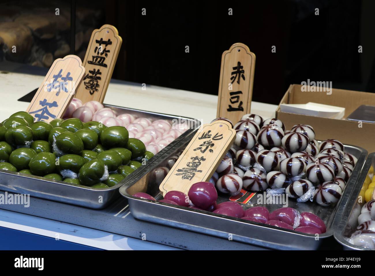 Matcha-, Blaubeer-, lila Süßkartoffel- und Rote-Bohnen-Geschmacksrichtungen traditioneller chinesischer klebriger Reiskuchen, die mit Geschmacksangabe auf dem Brett präsentiert werden Stockfoto
