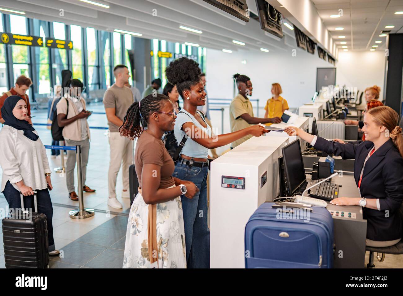 Verschiedene Passagiere, die am Flughafen bei den Fluglinienmitarbeitern einchecken Stockfoto