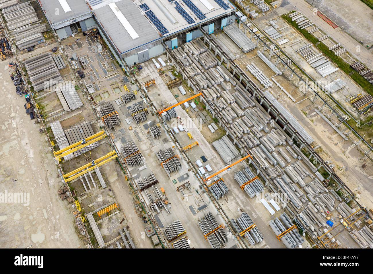 Luftbild eines Fabrikhofs mit Reihen von vorgespannten Betonelementen, Industriegebäuden und Krandurchfahrten in Polen. Stockfoto