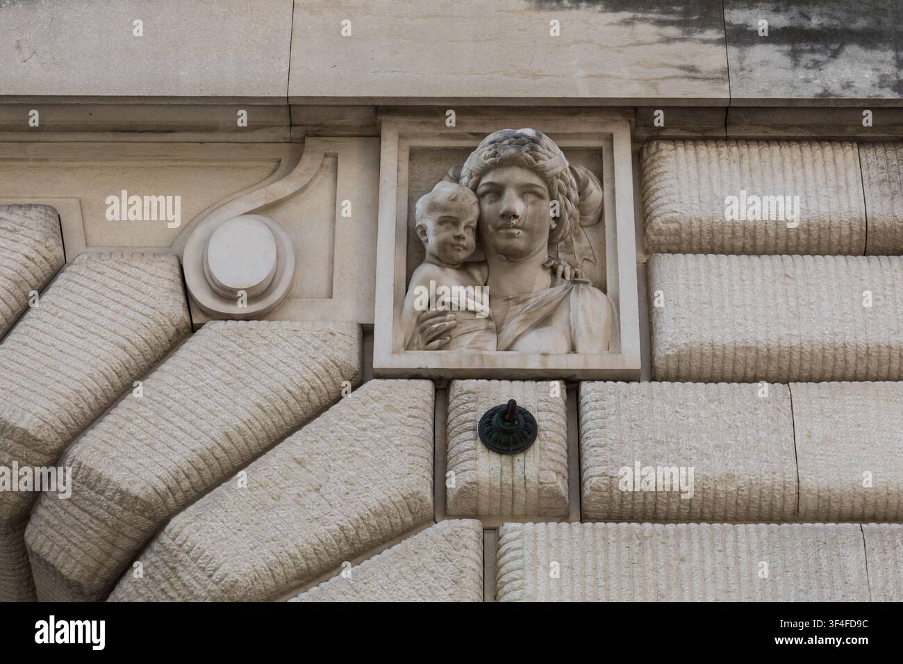 Geschnitztes Madonna-und-Kind-Relief, das in die Fassade eines historischen Steingebäudes in Udine, Friuli Venezia Giulia, Italien, eingelassen ist Stockfoto