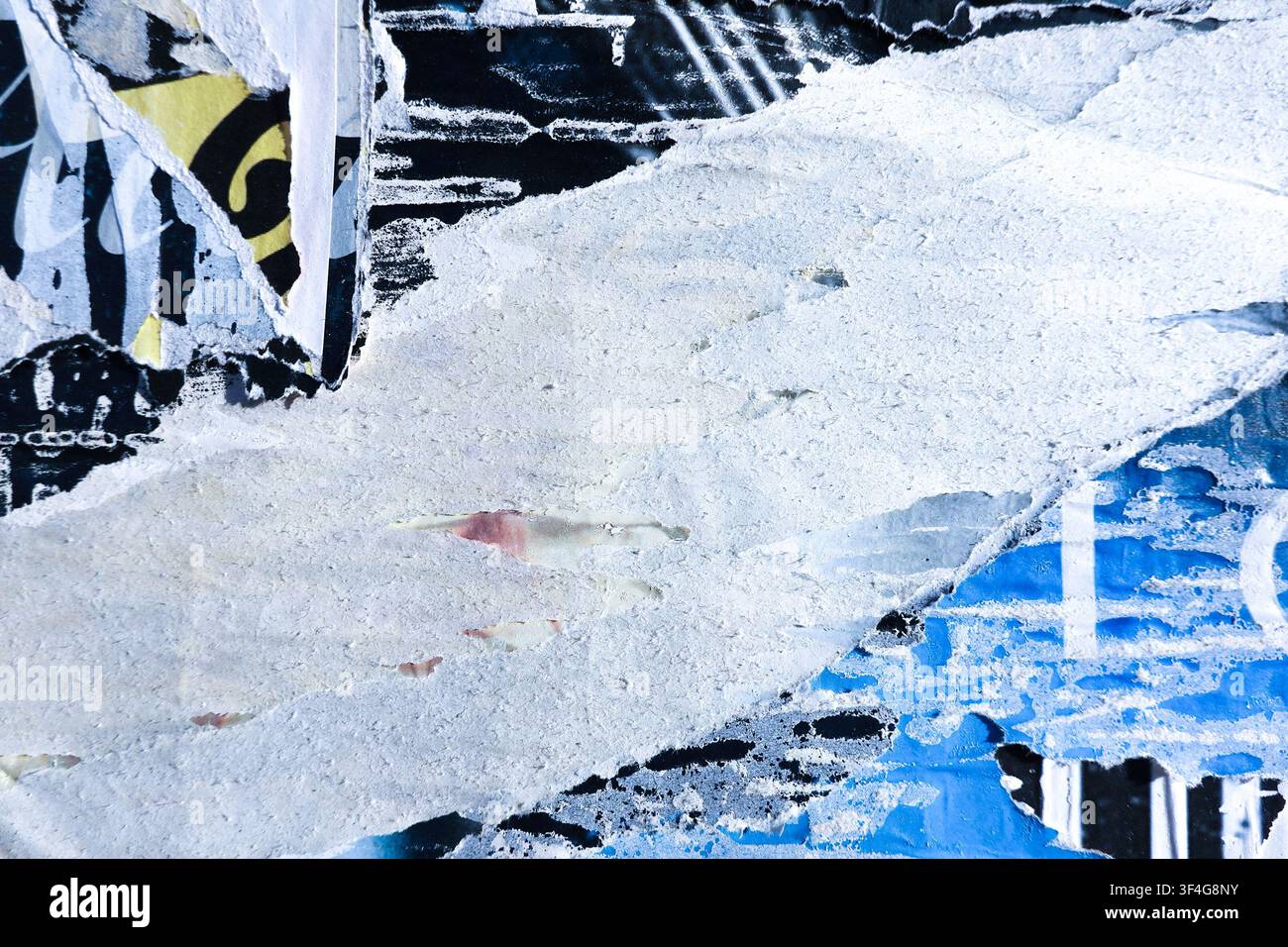 Strukturierte Oberfläche mit Schichten aus alten zerrissenen Papierplakaten und Farbe. Blaue, schwarze und weiße Farben Plakatstücke an der Wand Stockfoto