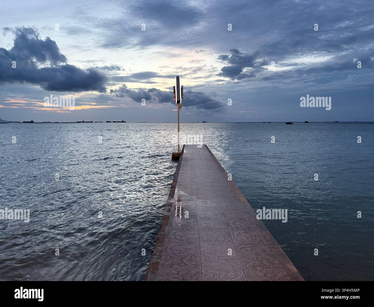 Vertikale Ansicht eines Meerespromenaden, die sich bei Dämmerung in Si Racha, Thailand, ins Meer erstreckt - Smartphone-aufgenommenes Stockfoto