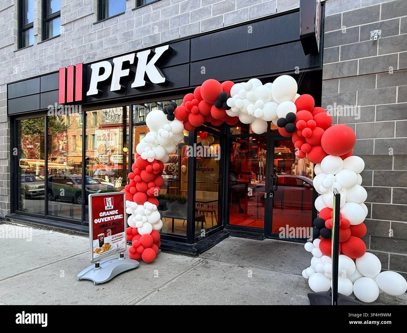 Neu eröffnetes PFK/KFC-Restaurant mit einem rot-weißen Ballonbogen zur Eröffnung in Montreal, Quebec, Kanada, der globale Fast-Food-Kultur veranschaulicht Stockfoto