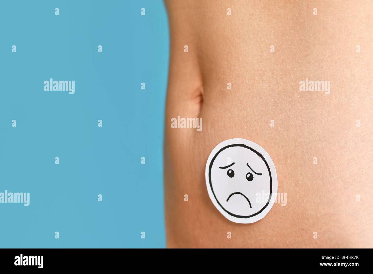 Trauriges Smiley auf dem Bauch einer Frau, das Menstruationsschmerzen, Endometriose, Fruchtbarkeitsprobleme und Probleme der reproduktiven Gesundheit symbolisiert, mit Kopierraum Stockfoto