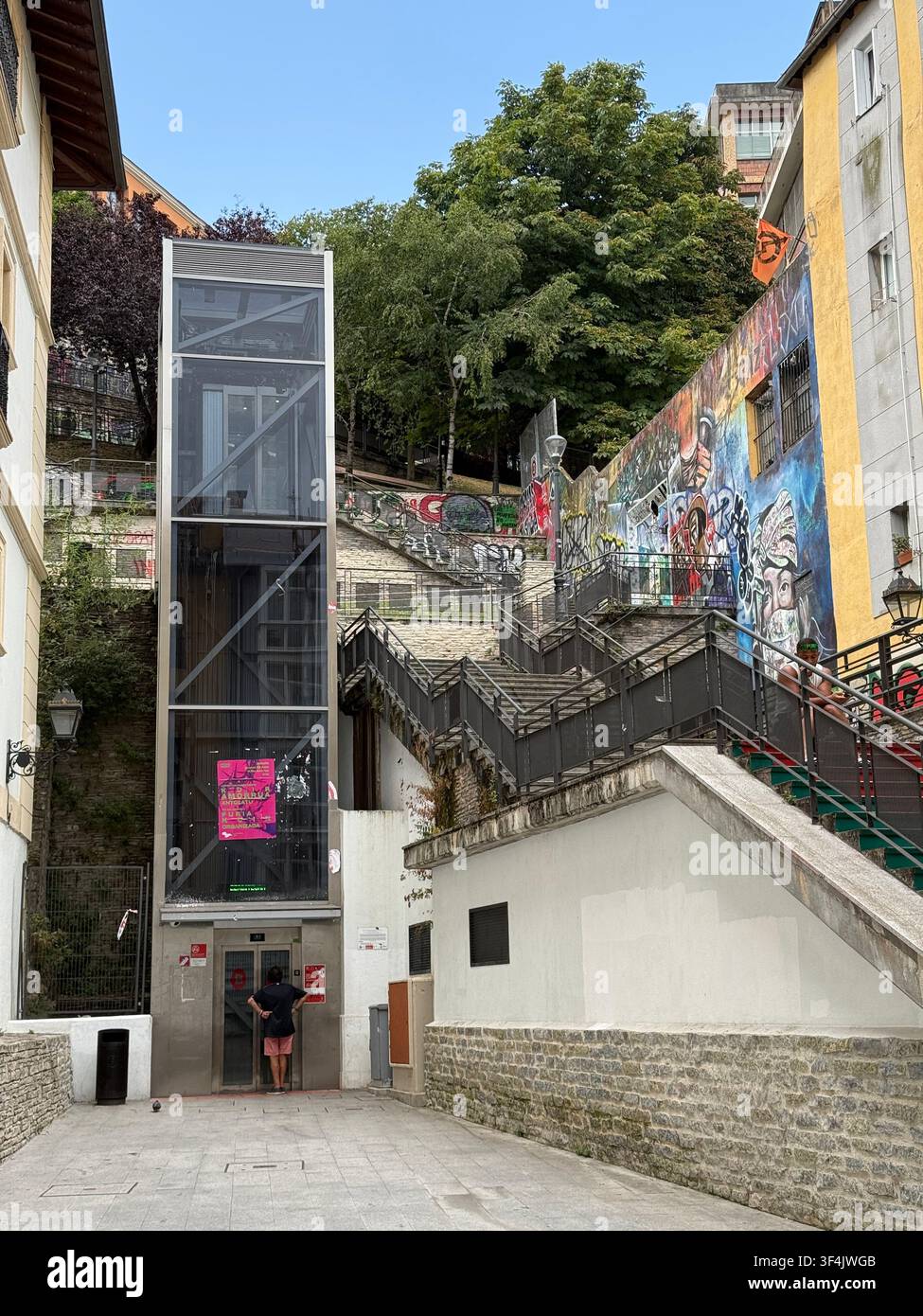 Öffentlicher Aufzug und mit Graffiti bedeckte Treppe, die einen steilen Hügel in Bilbao, Spanien, erklimmen. - Smartphone-aufgenommenes Stockfoto