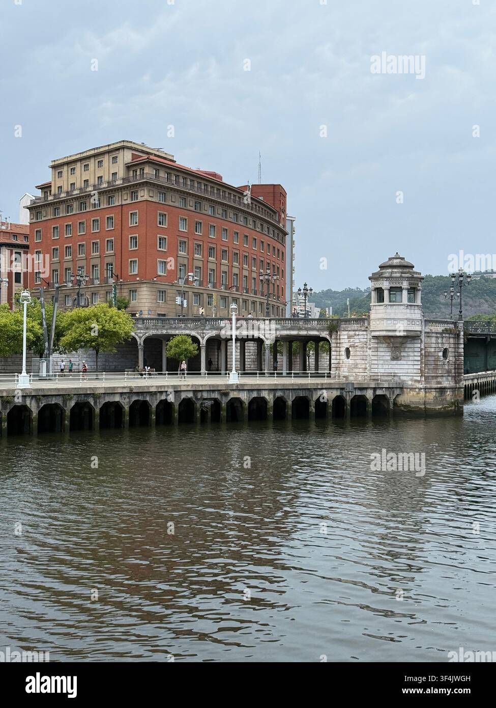 Historische Ufergebäude und ein Steinbrücken-Turm neben dem Nervión-Fluss im Zentrum von Bilbao, Spanien. - Smartphone-aufgenommenes Stockfoto