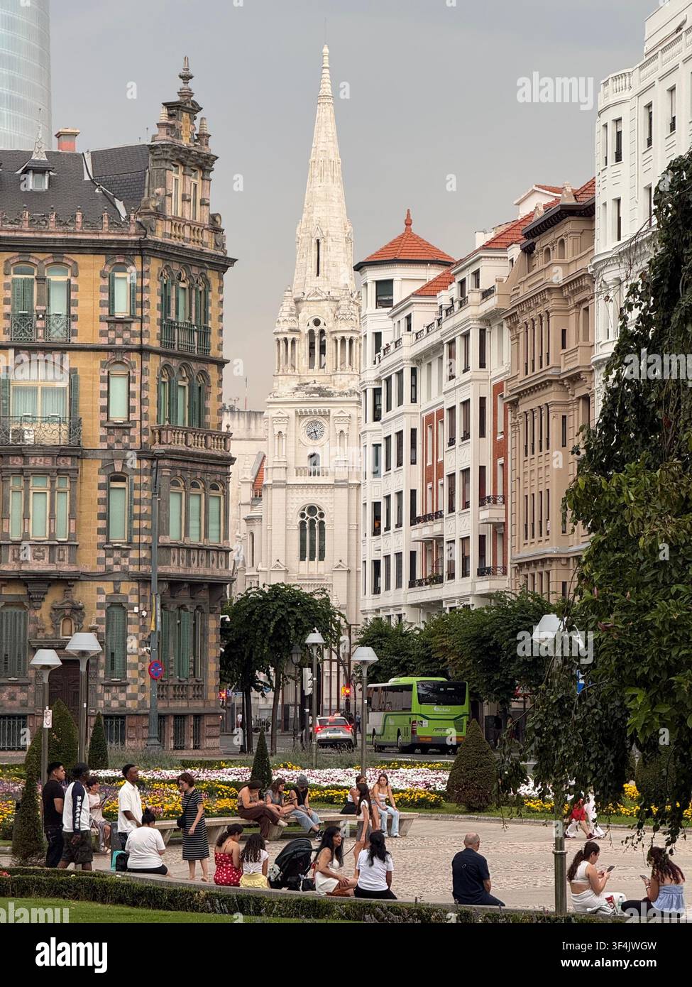 Menschen, die sich auf einem gestalteten Stadtplatz entspannen, der von historischer Architektur in der Innenstadt von Bilbao, Spanien, umgeben ist. - Smartphone-aufgenommenes Stockfoto