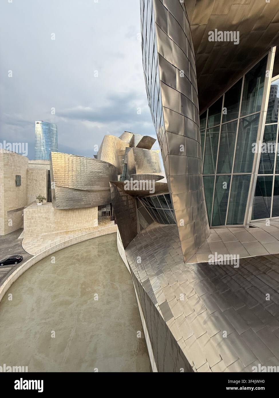 Titaniumkurven und reflektierende Oberflächen des Guggenheim-Museums Bilbao unter einem Abendhimmel in Spanien. - Smartphone-aufgenommenes Stockfoto