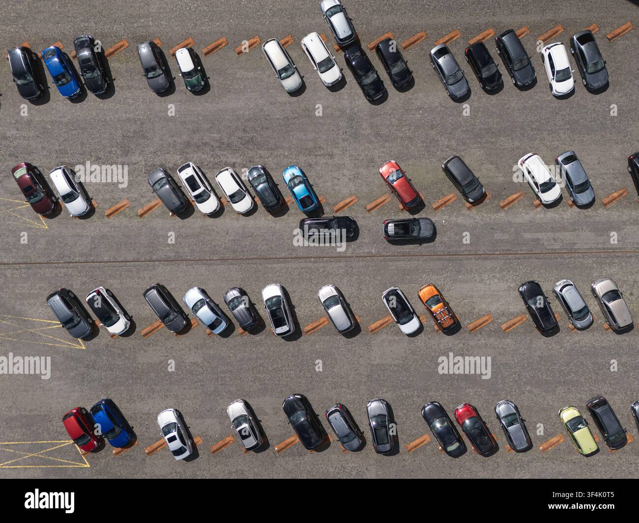 Luftbild von oben von Autos, die in Reihen auf einem großen Außenparkplatz geparkt sind, Konzept für urbane Verkehrsanlagen und Fahrzeuglagerung. Stockfoto