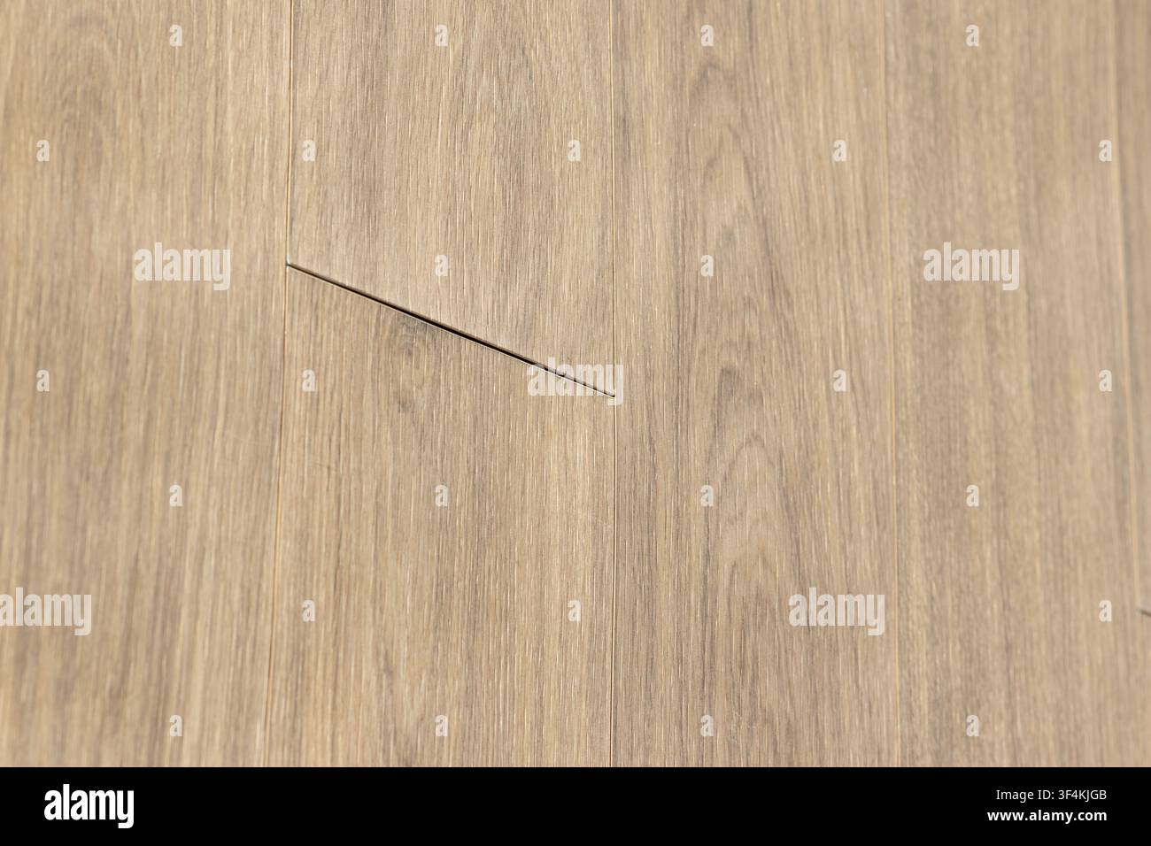 Hintergrund eines beschädigten Holzlaminenbodens mit angehobenem Fuge und Baufehler Stockfoto