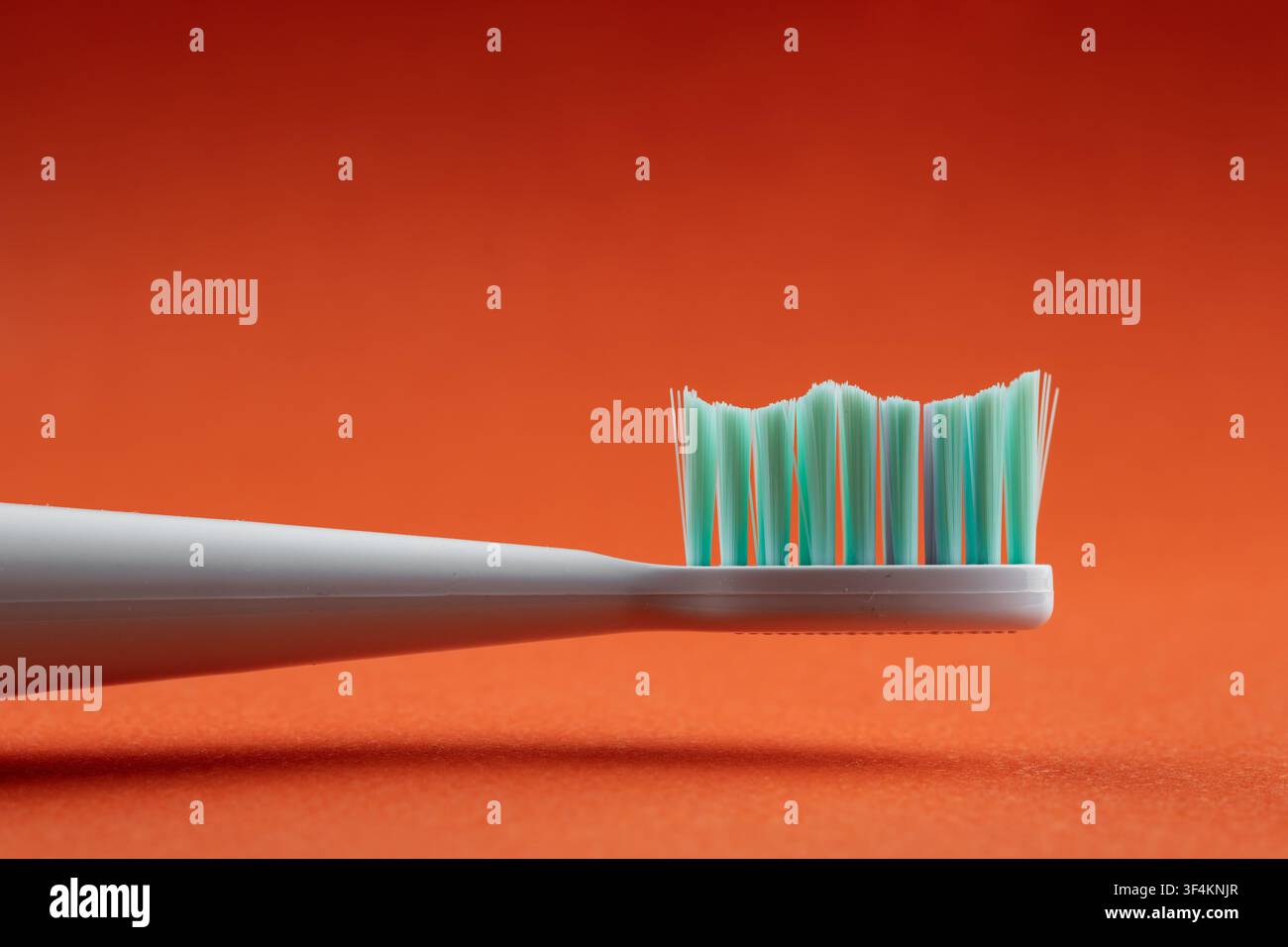 Zahnborsten, die Wellenmuster vor einem lebhaften orangefarbenen Hintergrund erzeugen, fördern die Mundhygiene Stockfoto