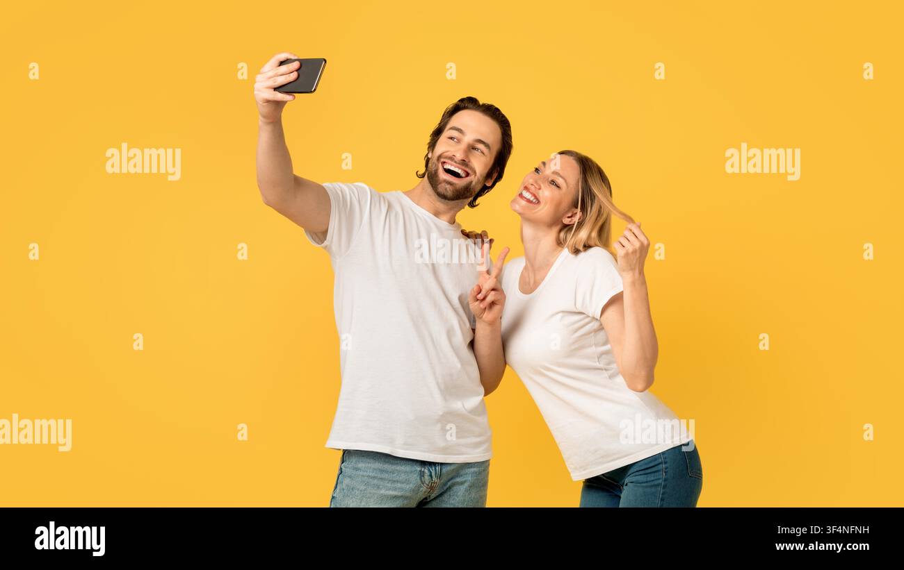 Glückliches junges Paar macht Selfie zu Hause, lächelt zusammen, freudiger Moment Stockfoto