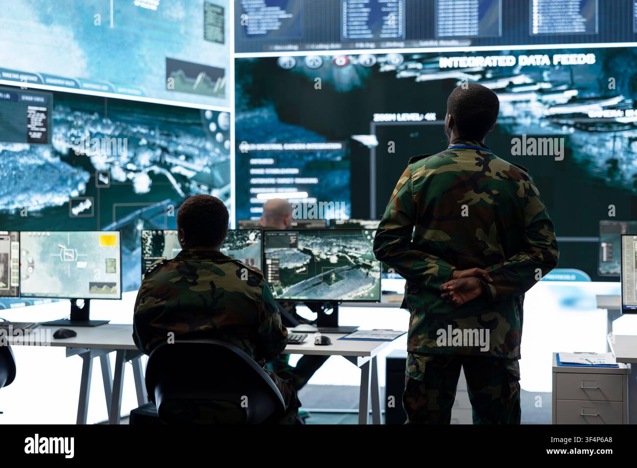 Armee-Vorgesetzter überwacht georäumliche Überwachungsdaten auf Bildschirmen im Militäroperationsraum. Team der Geheimdienstabteilung analysiert Satellitenkarten, um Aufklärungsinformationen für defensive Operationen zu sammeln Stockfoto