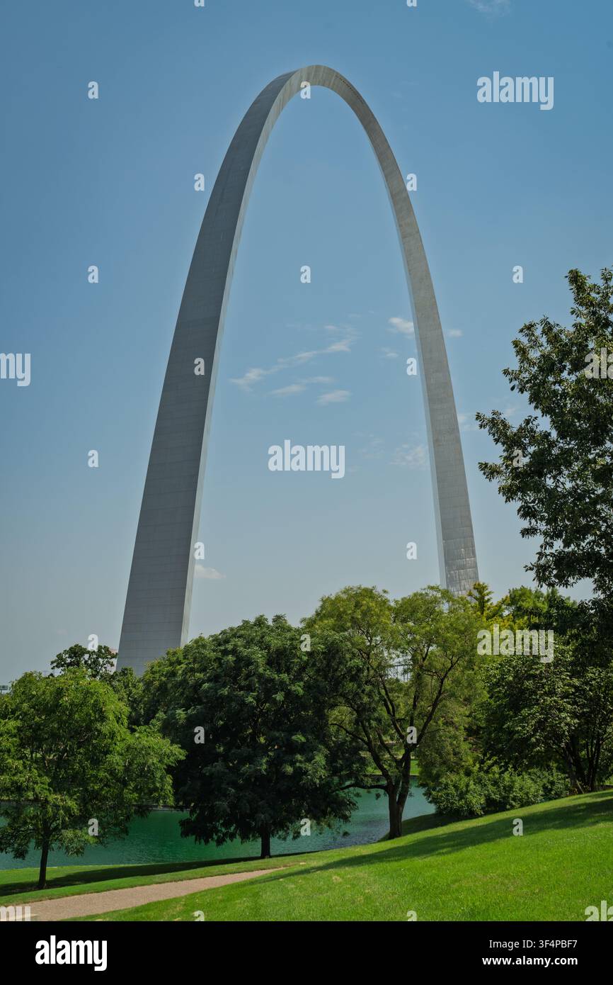 Der Gateway Arch ragt über üppige Parkbäume und einen ruhigen Teich unter einem klaren blauen Himmel in St. Louis, Missouri. Stockfoto