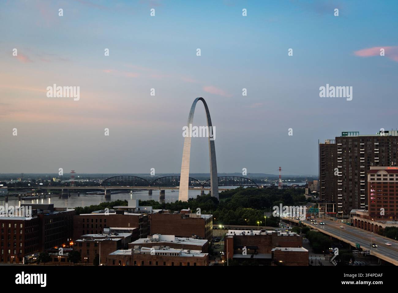 Das ikonische Gateway Arch erhebt sich über den Mississippi und die Skyline von St. Louis während eines farbenfrohen Zwielichts. Stockfoto
