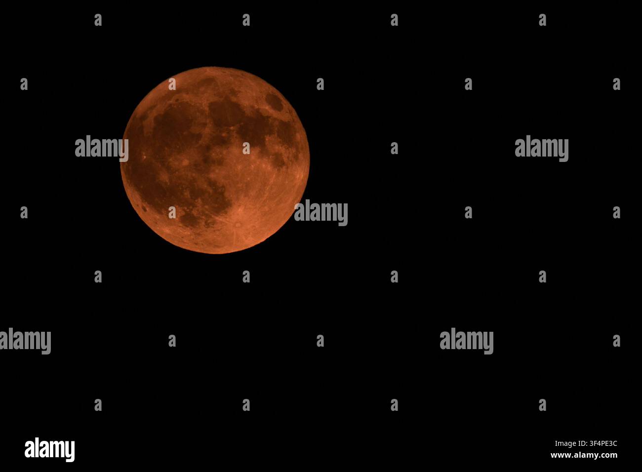 Detaillierter roter Hirsch-Vollmond, der während Juli in Griechenland gegen den dunklen Nachthimmel leuchtet und klare Oberflächend Krater sowie eine lebendige orangefarbene Atmosphäre zeigt. Stockfoto