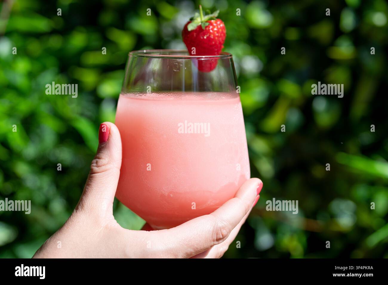 Erfrischendes Erdbeerdgetränk, genossen in einer üppigen Gartenumgebung Stockfoto
