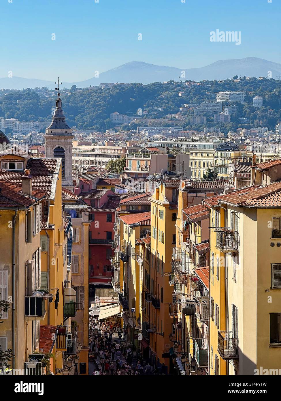 Erhöhte Ansicht über farbenfrohe Straßen, Dächer, Kirchturm und umliegende Hügel in Nizza an der französischen Riviera, Frankreich. Stockfoto