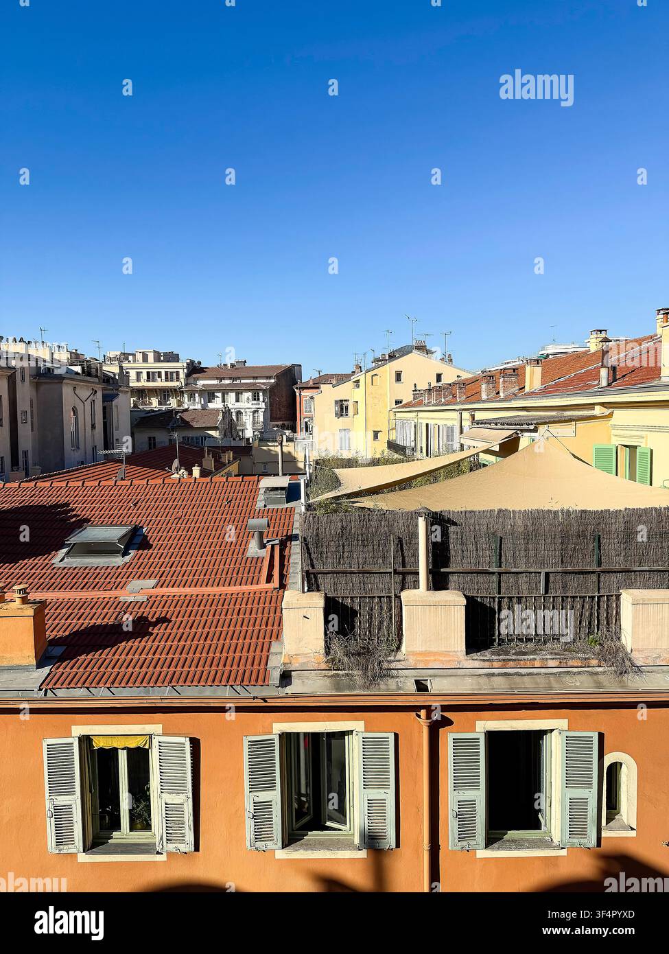 Blick über farbenfrohe Dächer und historische Gebäude in der Altstadt von Nizza mit traditioneller mediterraner Architektur unter einem klaren blauen Himmel. Stockfoto