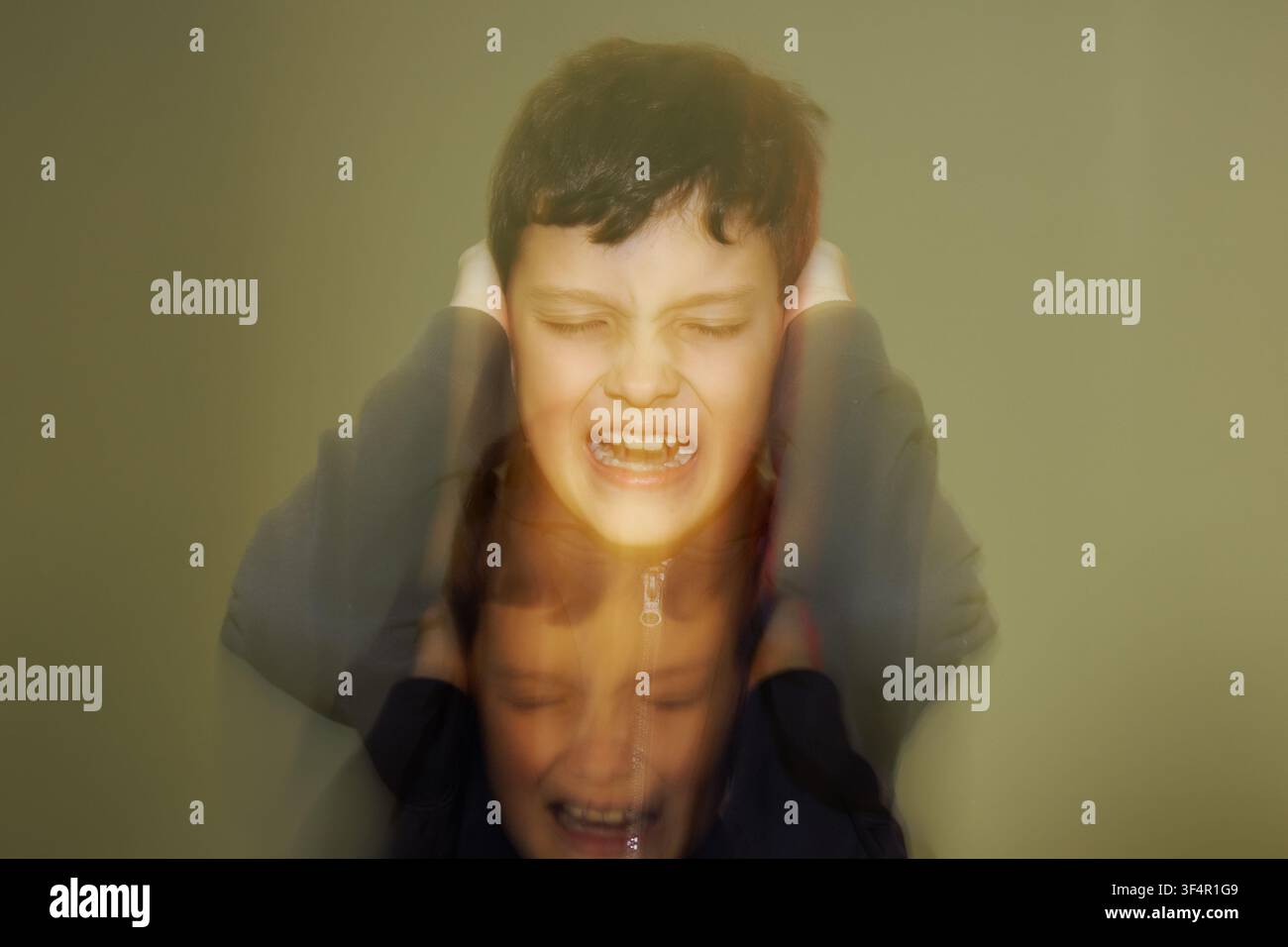Ein Teenager-Junge hält sich die Ohren und schreit vor negativen Emotionen, Wut und Schmerz. Spiegelung seines Gesichts wie eine Seele. Stockfoto