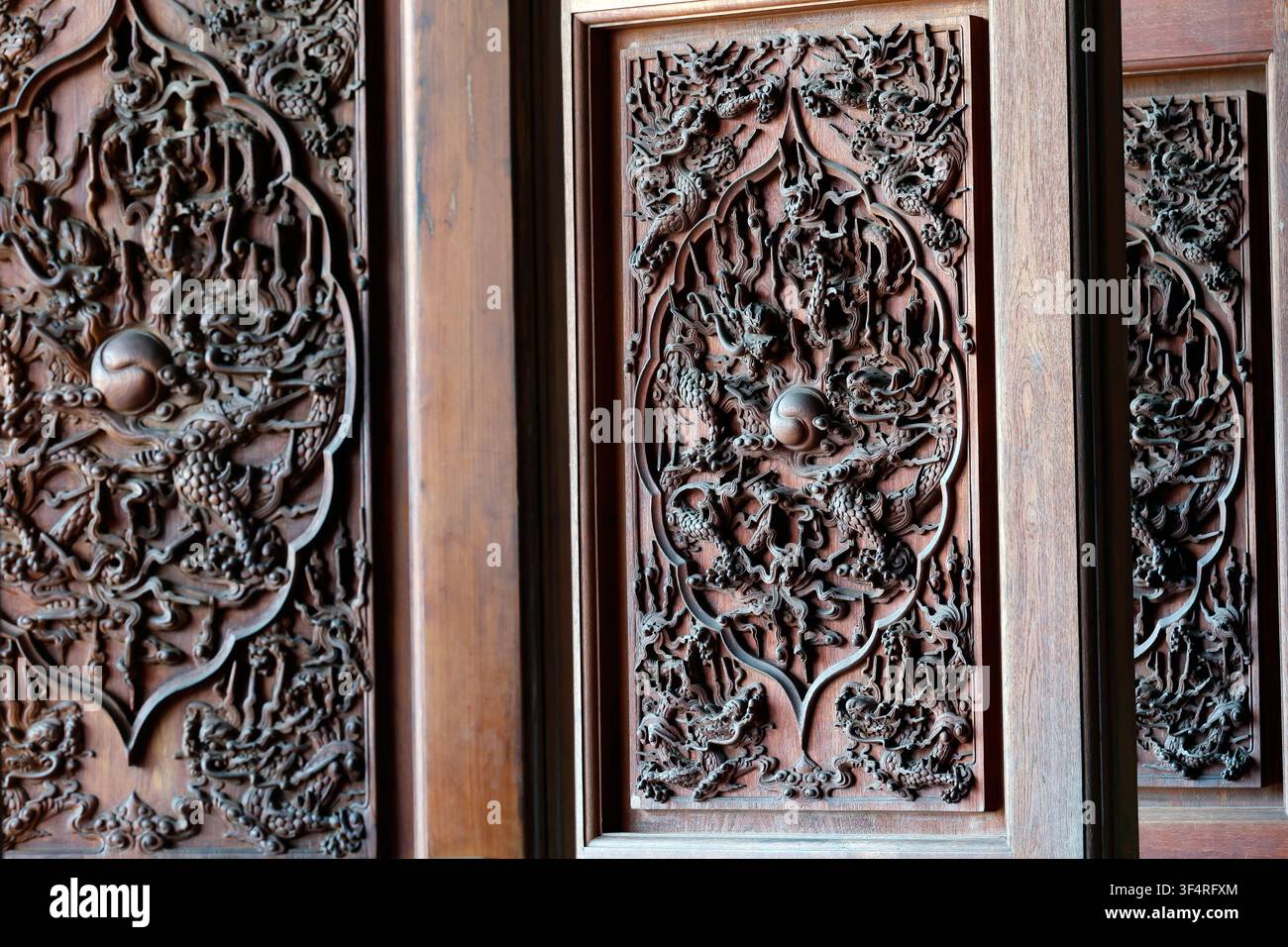 Quoc An Khai Tuong Pagode. Holztüren kunstvoll mit Drachenmotiven geschnitzt, die in der traditionellen asiatischen Kunst Macht und Glück symbolisieren. Long Phuoc Stockfoto