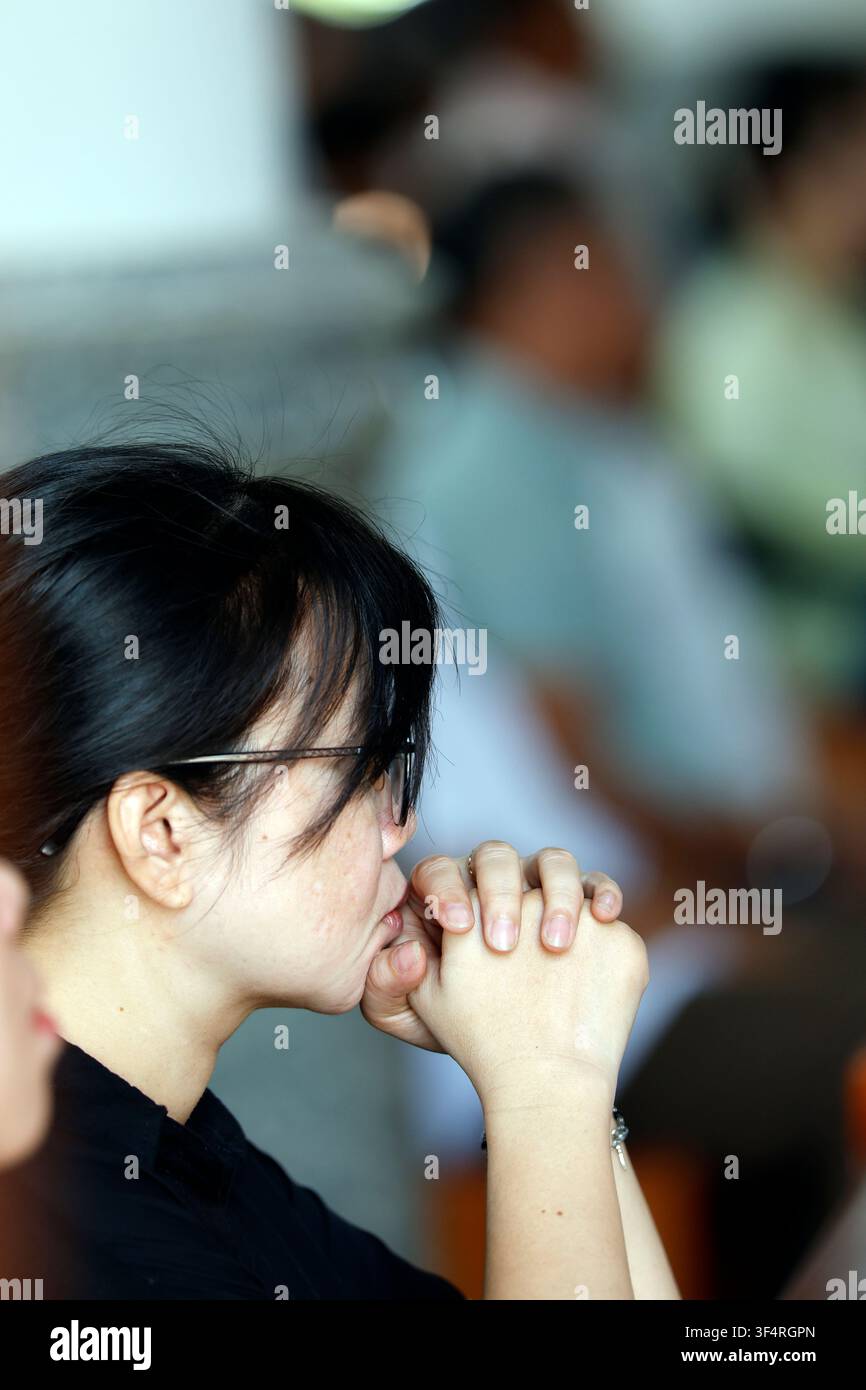 Eine Frau im Gebet, ihre Hände gefaltet, drückt ihren Glauben und ihre Hingabe aus. Sie ist in Gedanken versunken während eines Moments tiefer Spiritualität und Meditation. Stockfoto