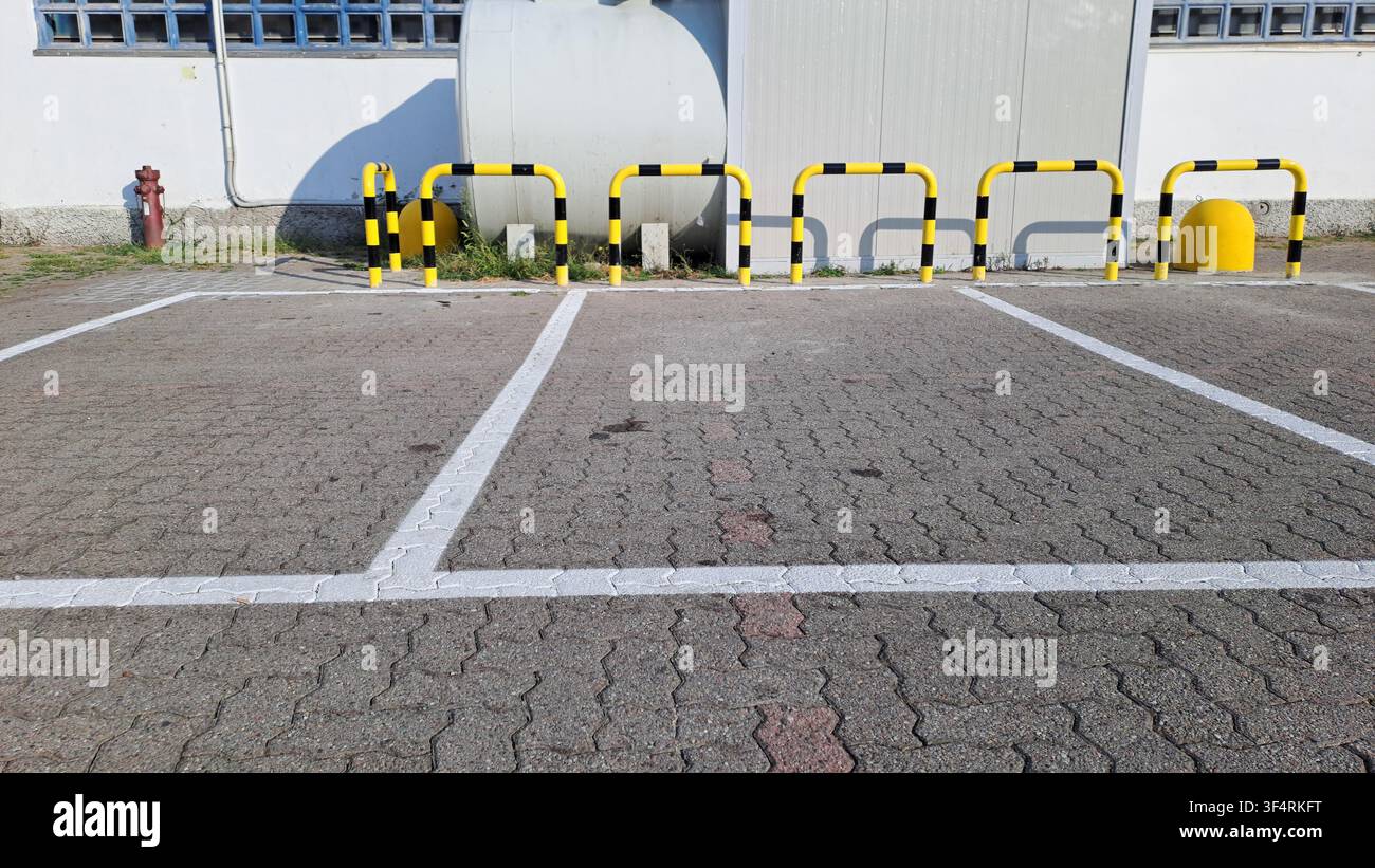 Schutzbarrieren auf einem Parkplatz zum Schutz eines großen Metallcontainers, einfache Bogen-Schutzbarriere Stockfoto