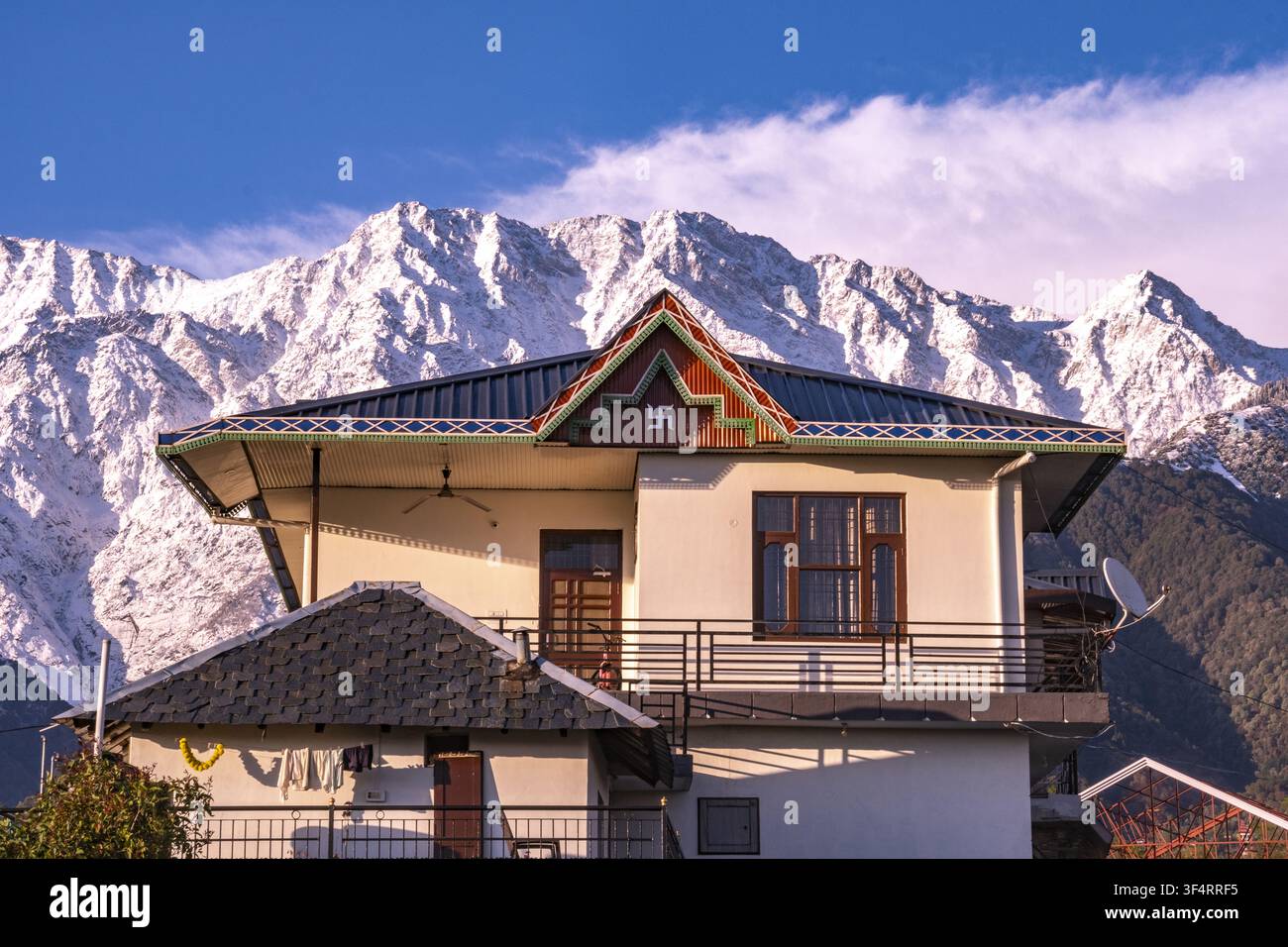 Ein Haus in Nagri, Himachal Pradesh, Indien, mit den Dhauladhar-Bergen im Hintergrund, verziert mit einem Swastika-Symbol Stockfoto