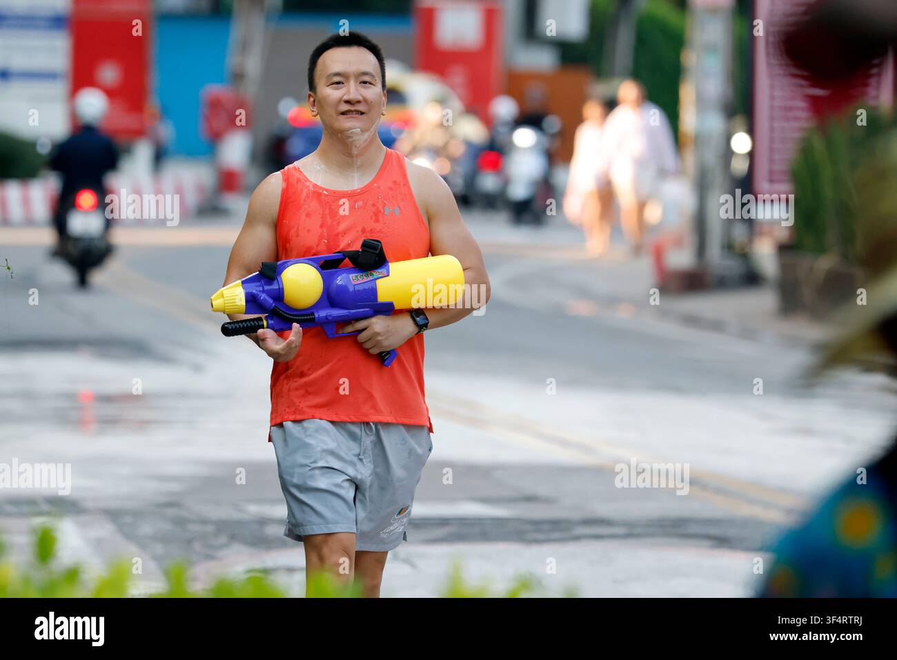 Ein lächelnder Mann hält eine Wasserpistole während der thailändischen Neujahrsfeiern, die als Songkran bekannt sind, einer fröhlichen und erfrischenden Tradition, die den Beginn von Stockfoto