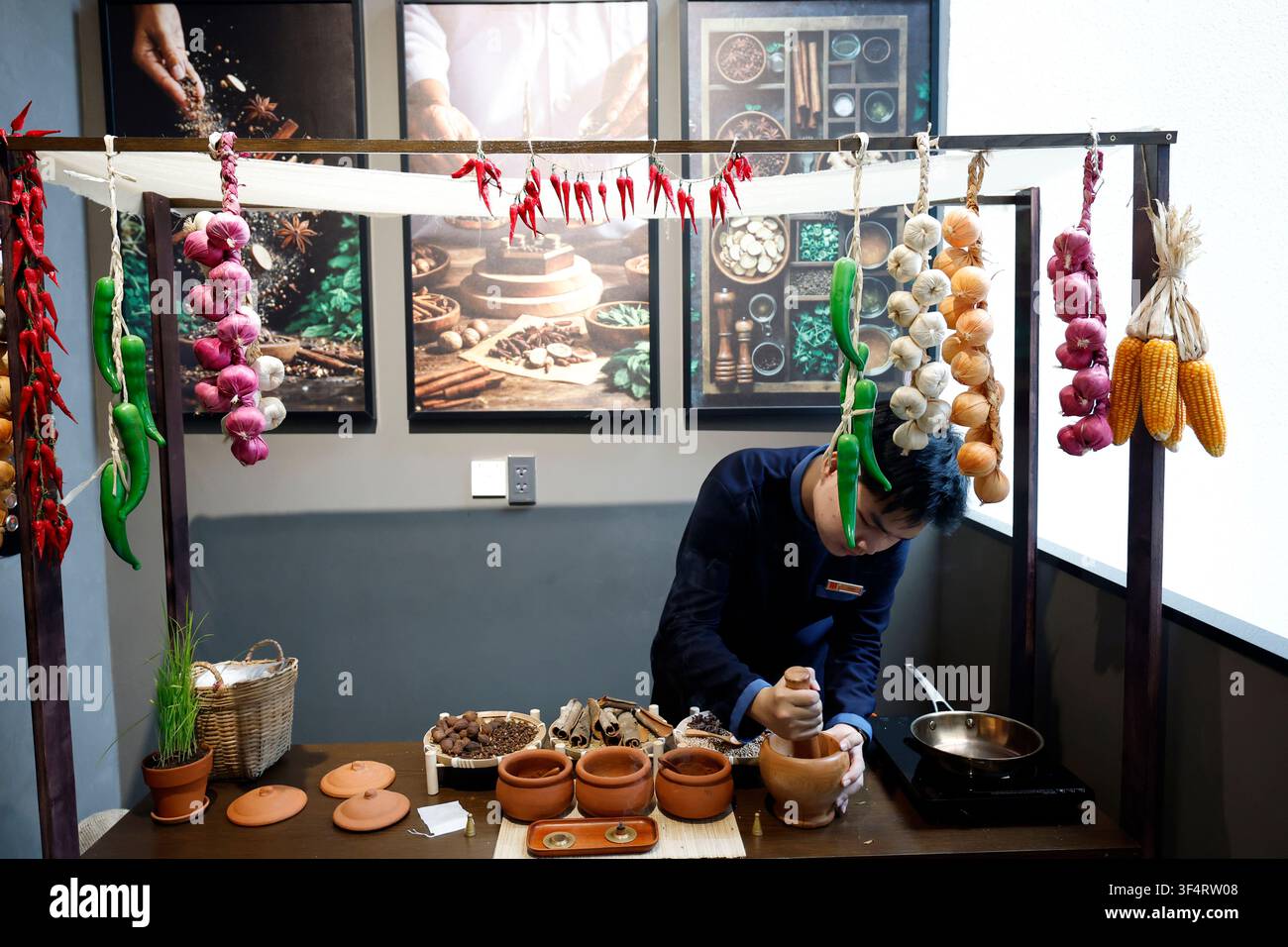 Ein Koch bereitet traditionelle Gewürze vor, indem er sie in einer Pfanne röstet. Die aromatischen Zutaten sind auf einem Tisch ausgelegt. Pho-Suppe. Ho-Chi-Minh-Stadt. Vietna Stockfoto