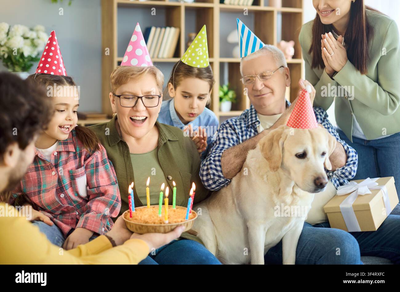 Fröhliche mehrgenerationenFamilie Geburtstag zu Hause mit Kuchen, Kerzen und Labrador Stockfoto