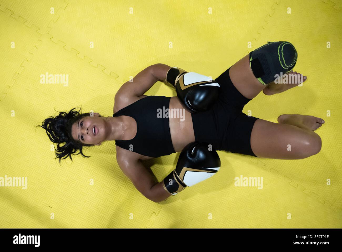 Ermüdete Boxerin liegt nach intensivem Training auf gelber Matte Stockfoto