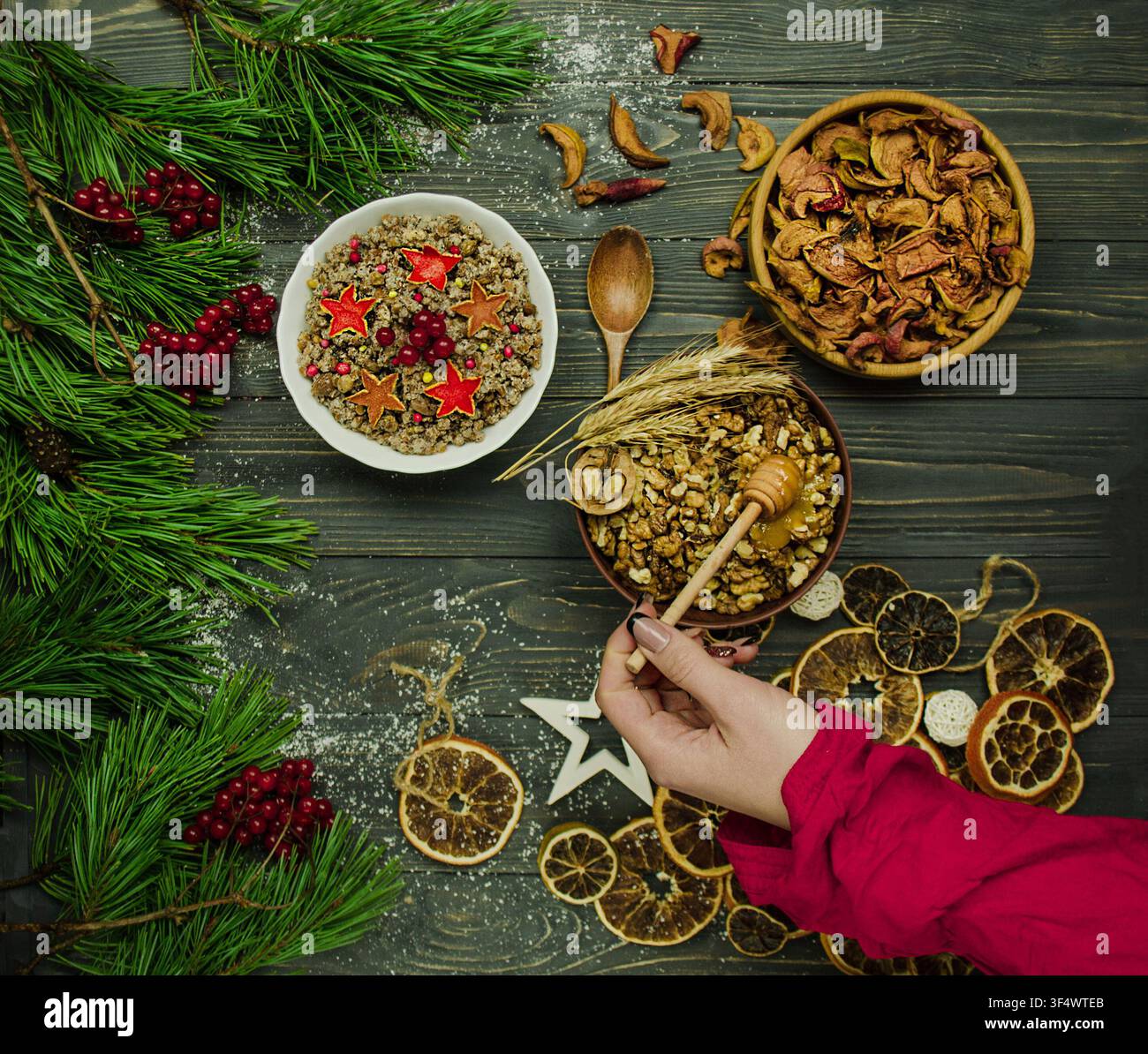 Traditionelles slawisches Feiertagsgericht Kutia wird in einer Holzschale neben Mais, Nüssen und Beeren auf dunklem Hintergrund bei Kerzenlicht präsentiert. Stockfoto