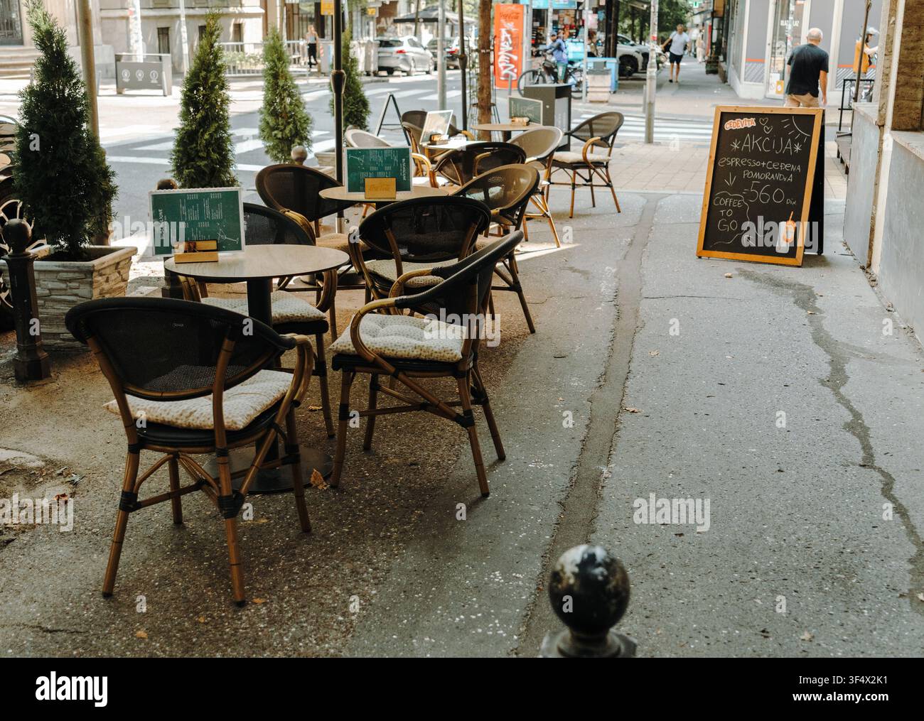 Belgrad, Serbien - 23. Juli 2026. Leere Tische und Stühle säumen eine schattige Straßencafé-Terrasse im Stadtzentrum. Stockfoto