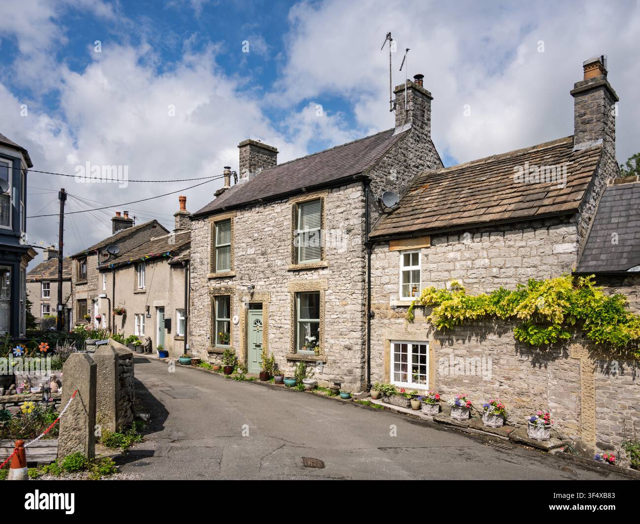 Traditionelle Kalksteinhäuser zeigen feine Steingewände und Sockelverzierungen entlang einer schmalen historischen Dorfstraße in Bradwell, Peak District, England Stockfoto