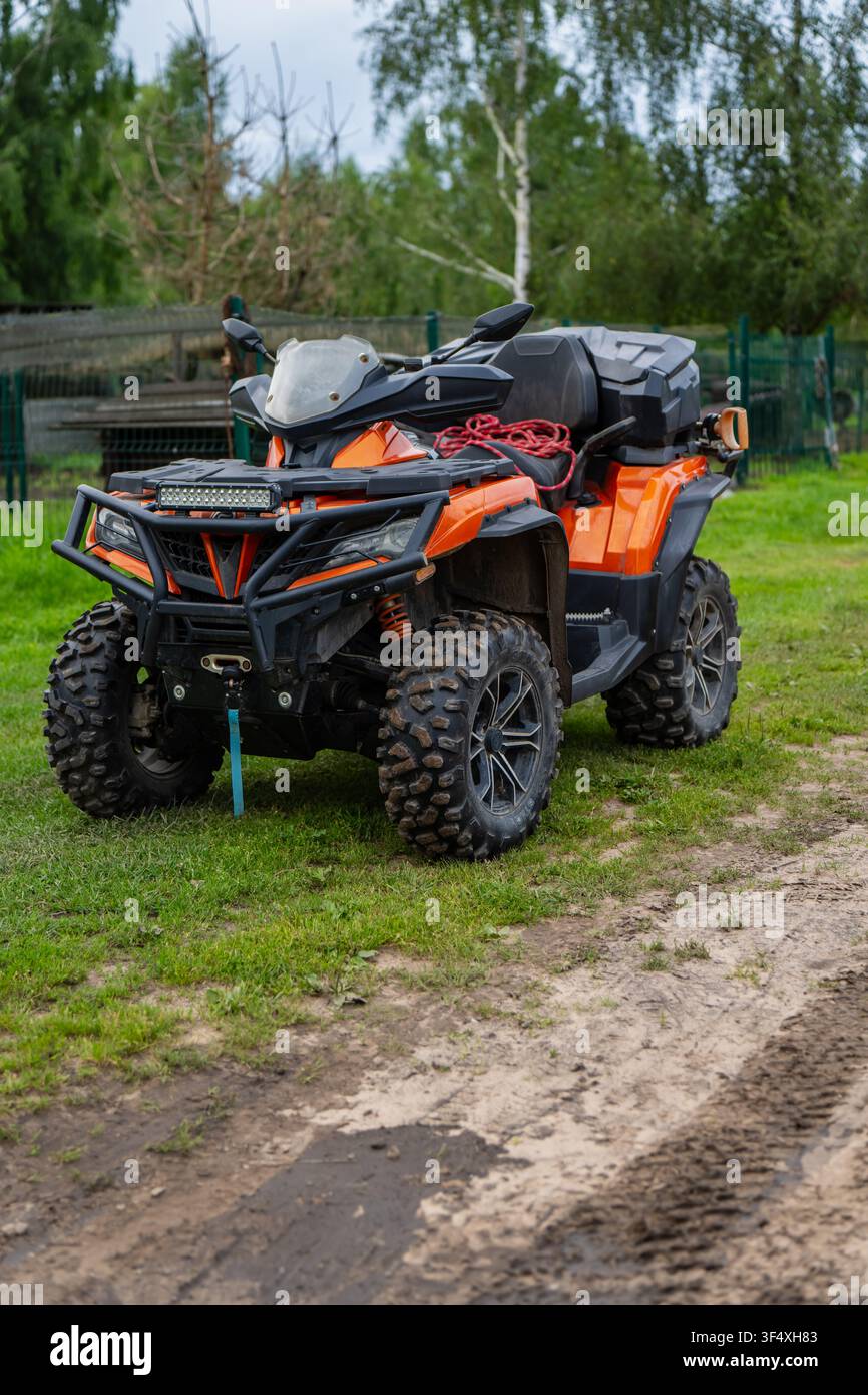 Orange Geländewagen ATV Quad Bike ausgestattet mit Off-Road-Bullbar, Seilwinde und Ladefläche, draußen geparkt, repräsentiert Nutzfahrzeug-Assets Stockfoto