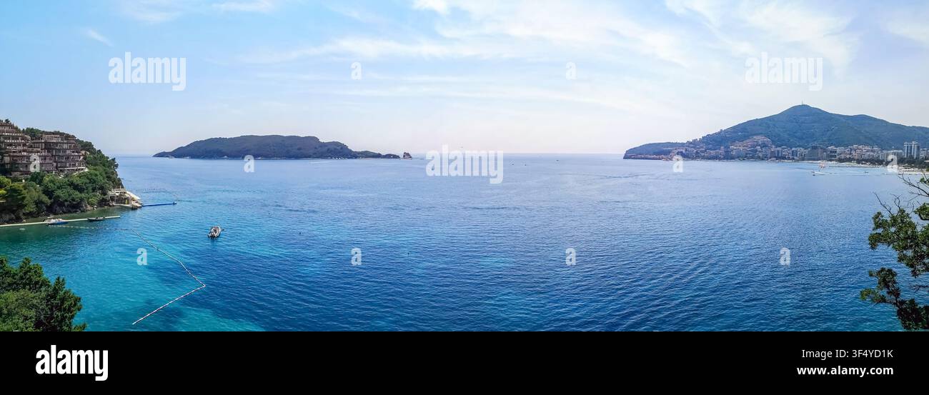 Weite Panoramasicht der Bucht von Budva und der Insel Sveti Nikola in Montenegro. Ruhiges türkisfarbenes Meer und grüne Hügel bilden eine malerische Küstenlandschaft Stockfoto