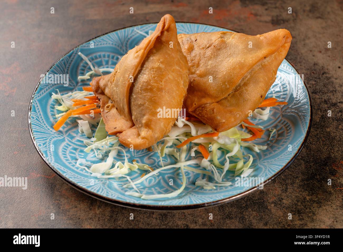 Authentische indische Hühnersamosas aus knusprigem dreieckigem Weizenblätterteig, gefüllt mit leicht gewürztem gehacktem Hühnchen, serviert mit frischer Kohlgarnitur Stockfoto