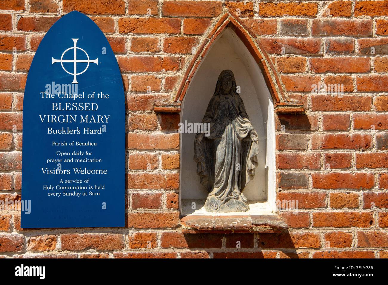 Blaues Schild und Steinstatue der seligen Jungfrau Maria in einer Backstein-Kapellen-Nische in Buckler's Hard Stockfoto