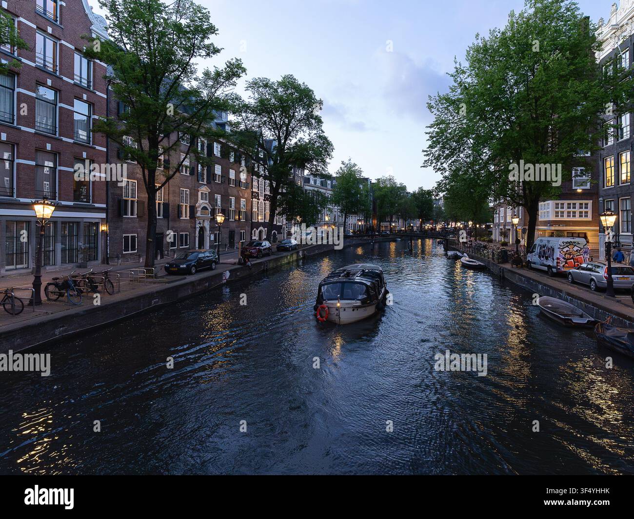 Atmosphärischer Kanalblick mit Booten und historischer Architektur in Amsterdam in der Dämmerung Stockfoto