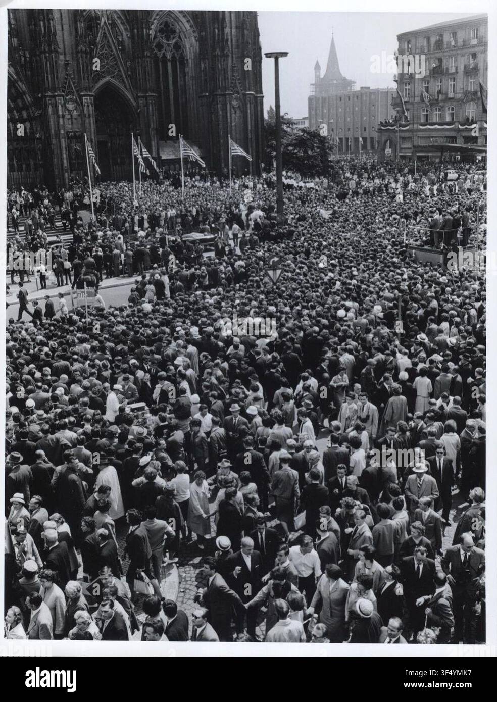 Schätzungsweise 25.000 Kölner Bürger warten vor der Kathedrale der Stadt, während 2.000 im Inneren mit Präsident John F. Kennedy, dem 35. Präsidenten der Vereinigten Staaten, der Messe beiwohnen. Stockfoto