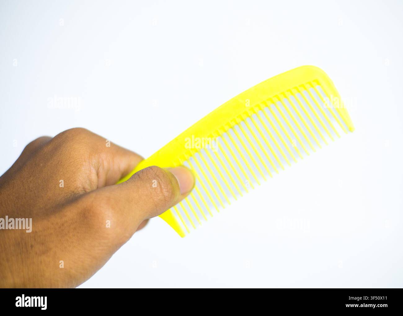 Gelber Plastikhaarkamm mit orangefarbenem Griff isoliert auf weißem Hintergrund Stockfoto